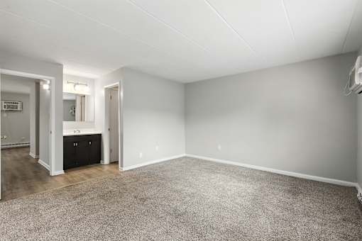 A spacious room with a carpeted floor and white walls.