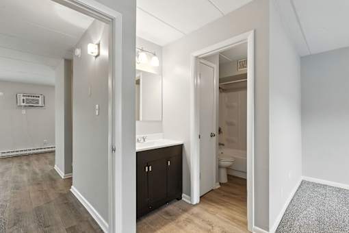A bathroom with a toilet, sink, and mirror is visible through an open door.