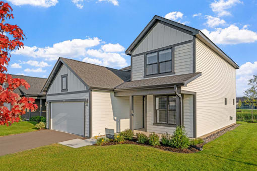 a white and gray house with a garage and a lawn