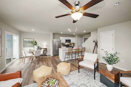 A modern living room with a ceiling fan and a dining area in the background.