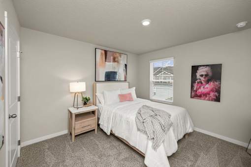 A bedroom with a bed, nightstand, and two pictures on the wall.