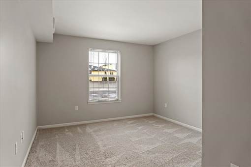 A room with a carpeted floor and a window.