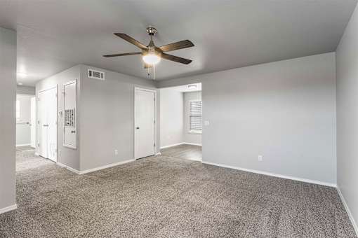 A room with a ceiling fan and carpeted floor.