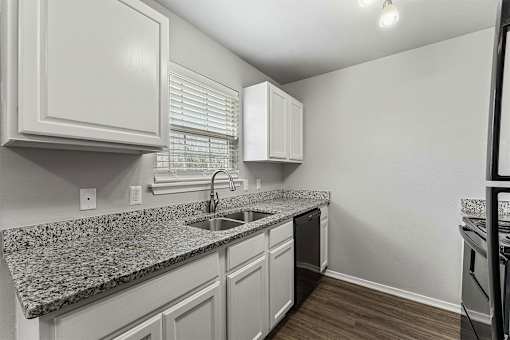 A kitchen with granite countertops and white cabinets.