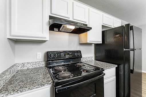 A black stove top oven sits next to a black refrigerator in a kitchen.