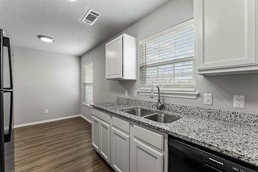 A kitchen with granite countertops and white cabinets.