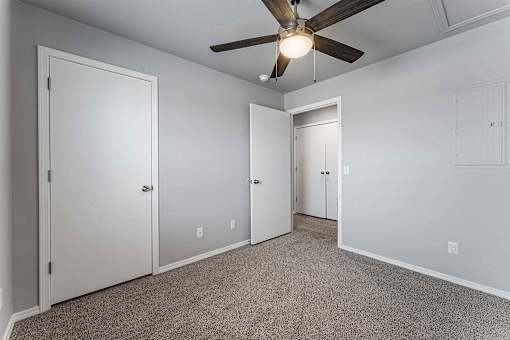 A room with a ceiling fan and three doors.
