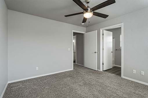 A room with a ceiling fan and carpeted floor.