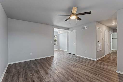 A room with a ceiling fan and wood flooring.