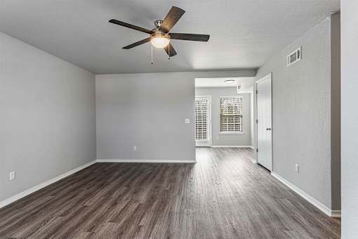 A room with a ceiling fan and wooden flooring.