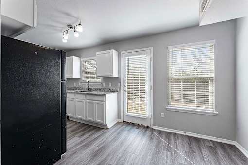 A kitchen with white cabinets and a black refrigerator.