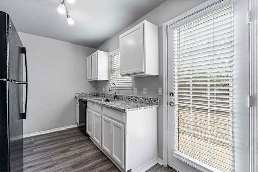 A kitchen with white cabinets and a black refrigerator.