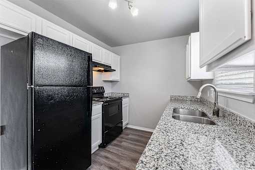A black fridge in a kitchen with a granite counter top.