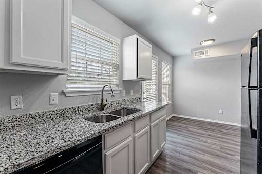 A kitchen with granite countertops and a black dishwasher.