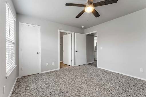 A room with a ceiling fan and carpeted floor.