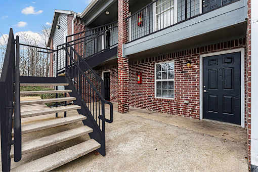 A black metal staircase with a black door and a black railing.
