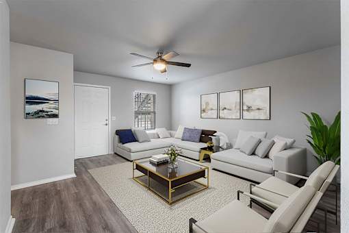 A living room with a white couch, a coffee table, and a ceiling fan.