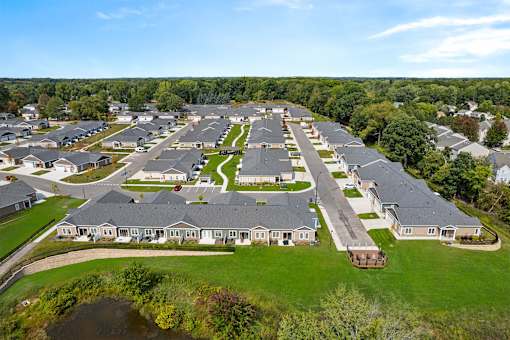 A bird's eye view of a residential area with houses and a pond.