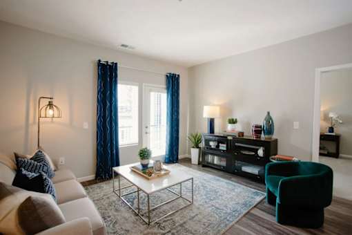 A living room with a white couch, a coffee table, a green armchair, and a bookshelf.