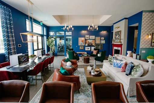 A living room with a white couch, red chairs, and a coffee table.