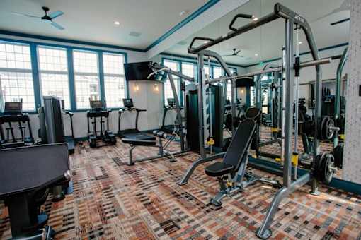 A gym with a variety of equipment including a squat rack, bench, and weights.