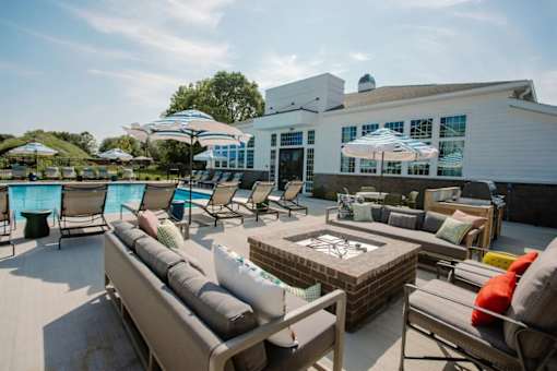 A patio with a table and chairs and a pool in the background.