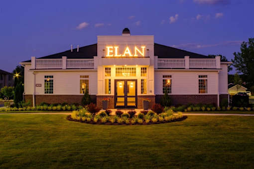 A white building with the word ELAN on it is lit up at dusk.