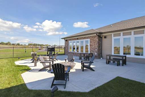 A sunny day at a patio with a table and chairs.