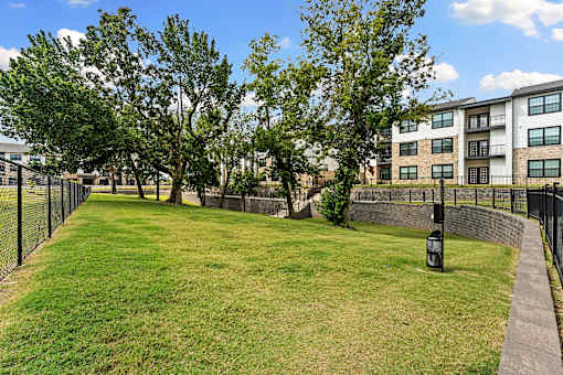 A grassy area with a fence and a building in the background.
