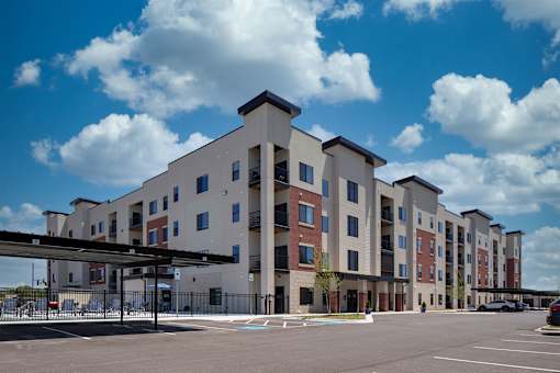 A large apartment complex with a parking lot in front.