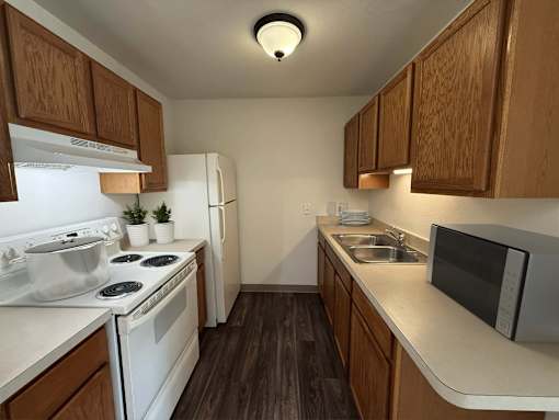 A kitchen with white appliances and wooden cabinets.