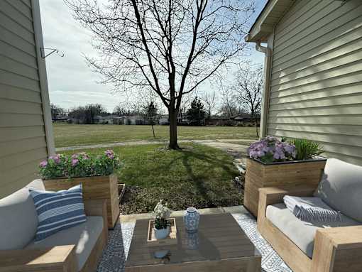 A backyard with a table, chairs, and a tree.