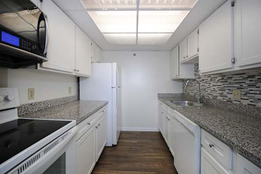 A kitchen with white cabinets and granite countertops.