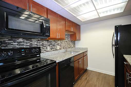 A kitchen with black appliances and wooden cabinets.