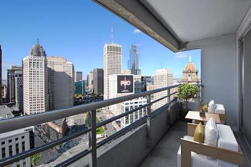 A balcony with a table and chairs overlooking a cityscape.