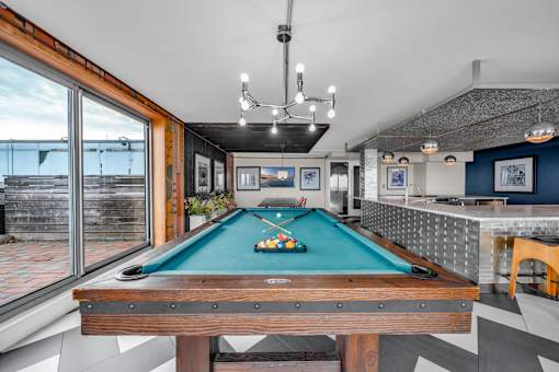 A pool table in a room with a high ceiling and a view of the outside.