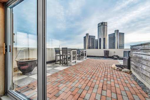 A balcony with a table and chairs overlooking a city skyline.