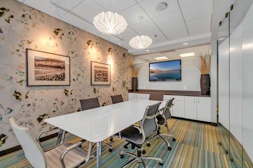 A conference room with a white table and chairs.