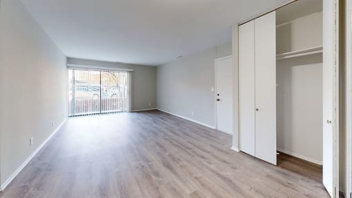 an empty living room with wood flooring and a window