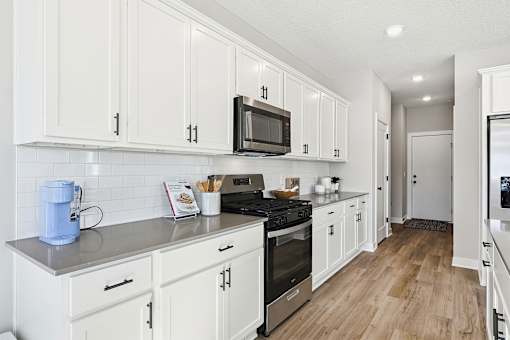 A kitchen with white cabinets and a blue coffee maker.