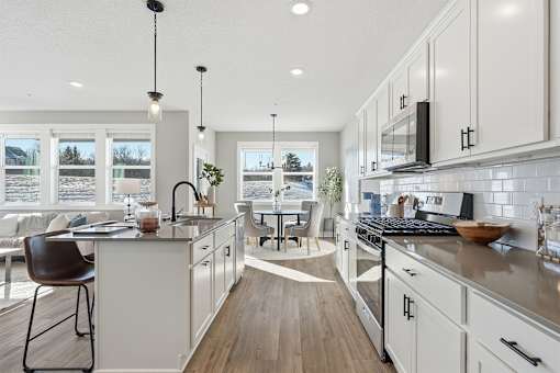 A modern kitchen with white cabinets and a wooden floor.