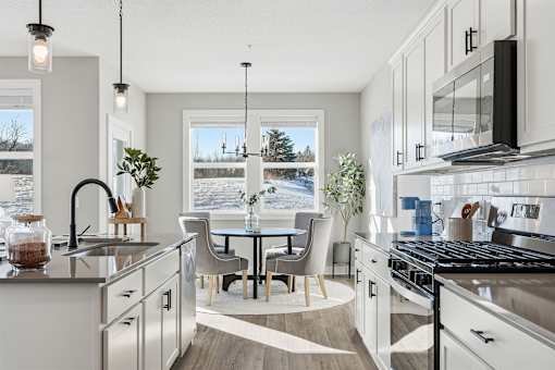 A modern kitchen with a large island and a view of the outdoors through the windows.