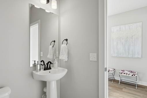 A white bathroom with a sink, mirror, and toilet.