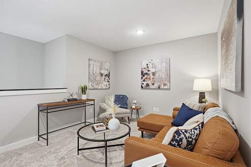 A living room with a brown couch, a coffee table, and two paintings on the wall.
