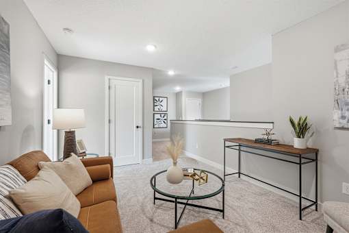 A living room with a brown couch, a glass coffee table, and a white lamp.
