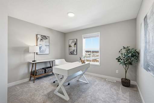 A room with a white desk and a plant.