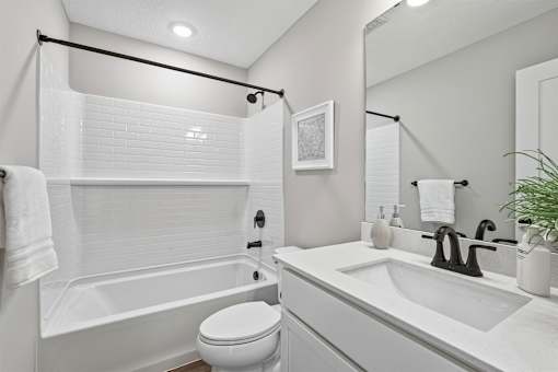 A white bathroom with a toilet, sink, and bathtub.