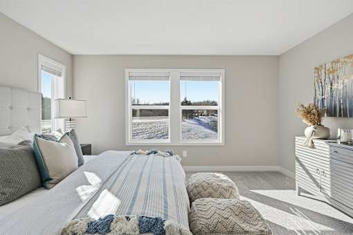 A bedroom with a large bed and a window overlooking a snowy landscape.