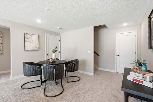 A living room with a black table and chairs.
