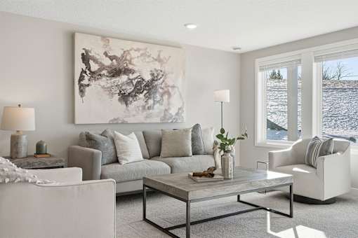 A living room with a grey couch, a coffee table, and a large painting on the wall.